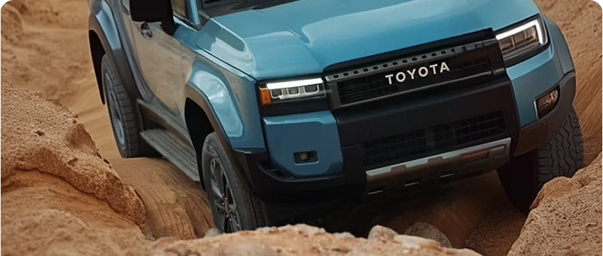 Blue 2027 Toyota Land Cruiser crawling down a steep red sand slope
