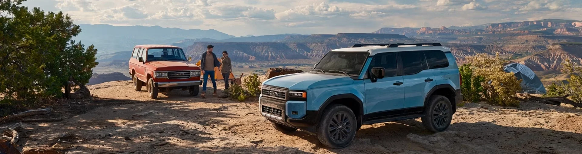 A vintage and a 2027 Toyota Land Cruiser parked side by side on a canyon overlook