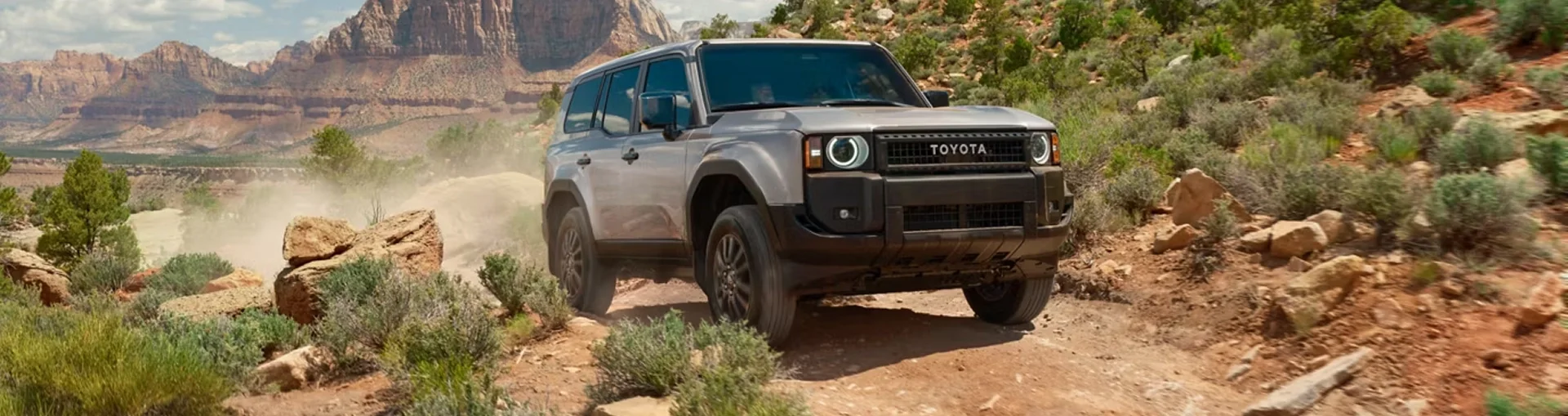 Gray 2027 Toyota Land Cruiser kicking up dust on a desert trail