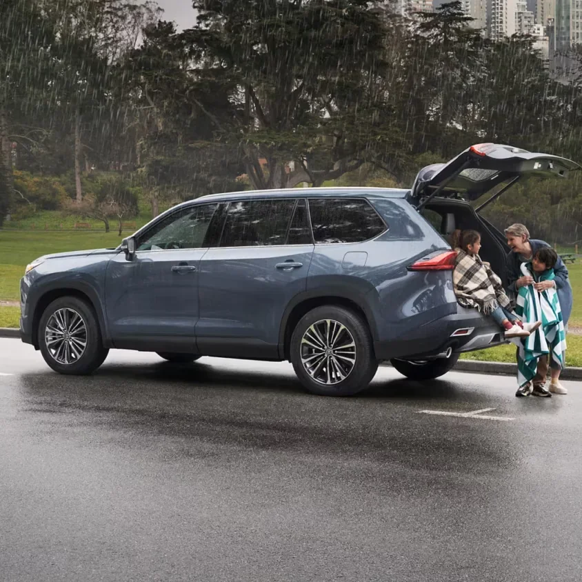 A family loading up the open liftgate of a 2026 Toyota Grand Highlander in the rain — Dalton Toyota National City