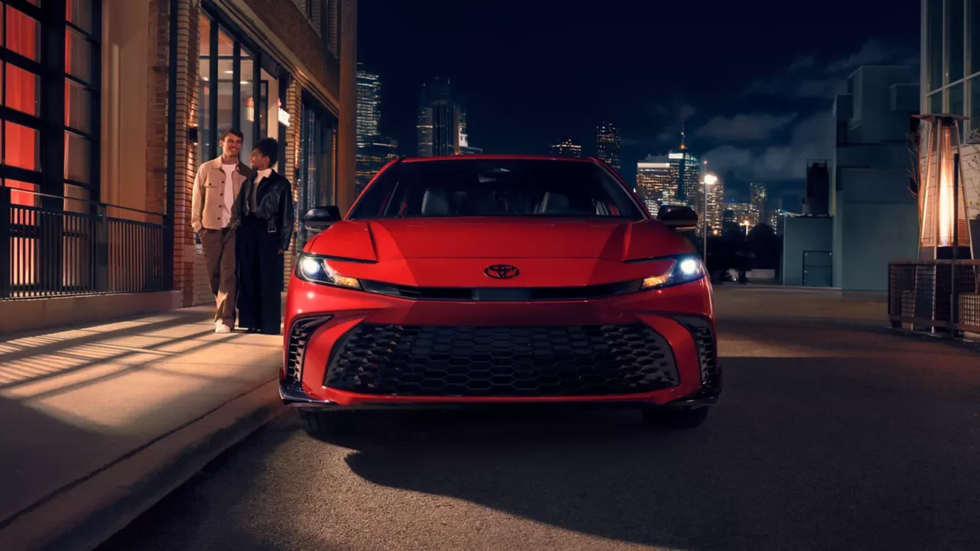 Red 2026 Toyota Camry on a city street at night with the downtown skyline behind it — Dalton Toyota National City