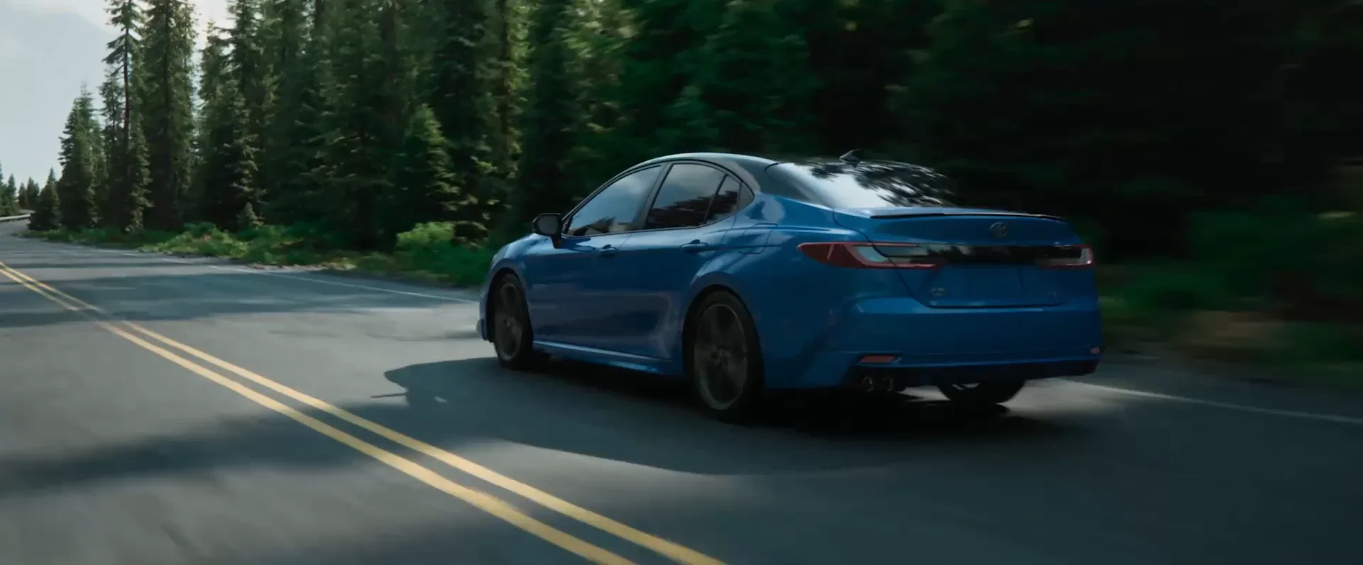 Blue 2026 Toyota Camry driving a forest highway — Dalton Toyota National City