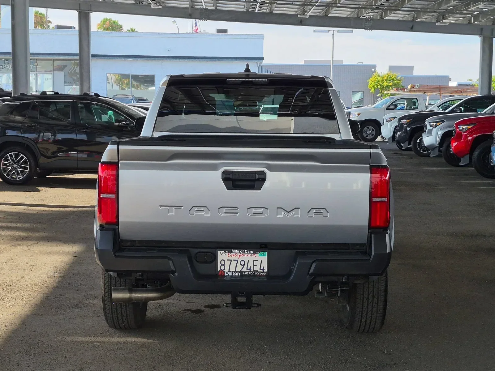 Silver 2025 Toyota Tacoma SR, rear view with TACOMA tailgate and Dalton Mile of Cars plate frame, at Dalton Toyota National City