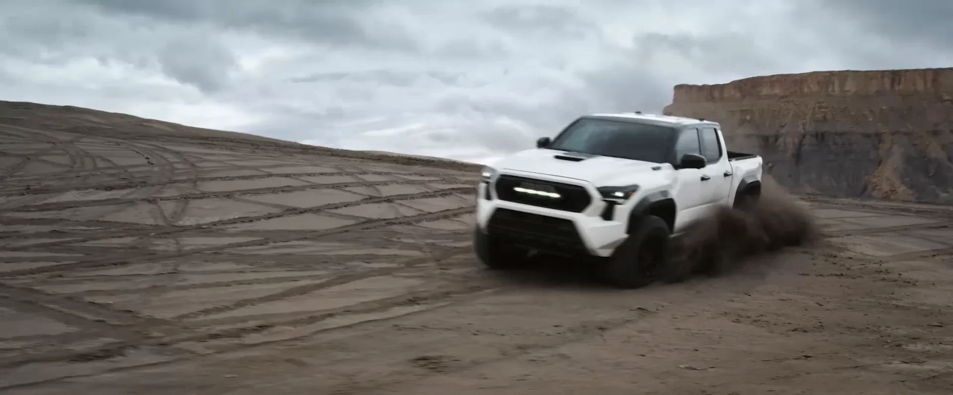 White Toyota Tacoma kicking up dirt on a desert trail — used trucks at Dalton Toyota National City