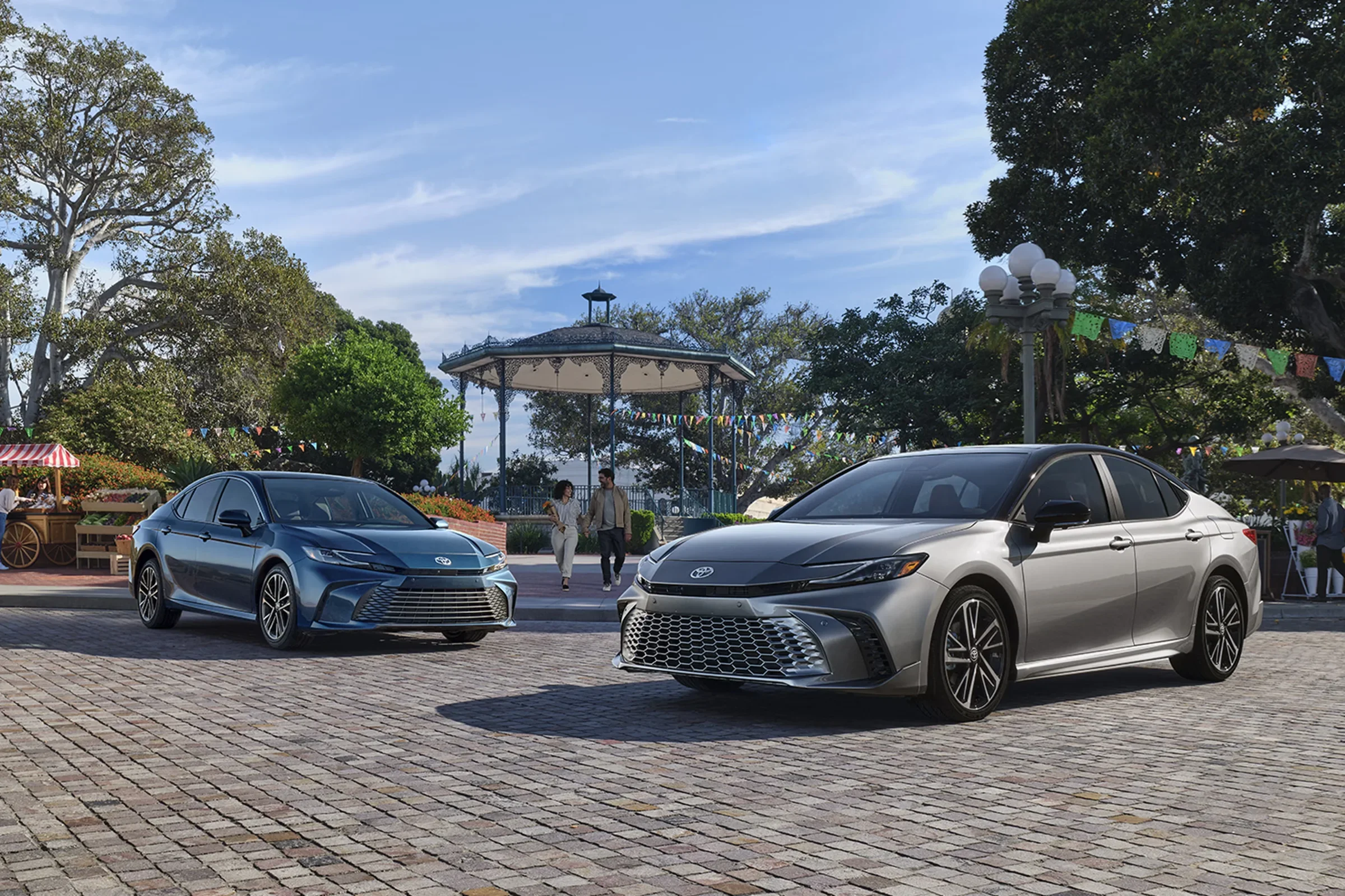 Two Toyota Camry sedans, one blue and one silver, parked on a plaza