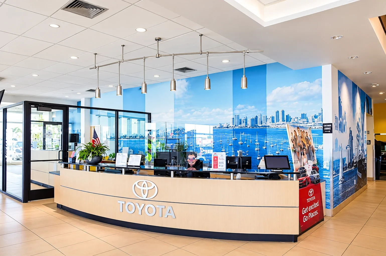 The front desk at Dalton Toyota National City, the Toyota logo on the counter and a San Diego Bay mural behind
