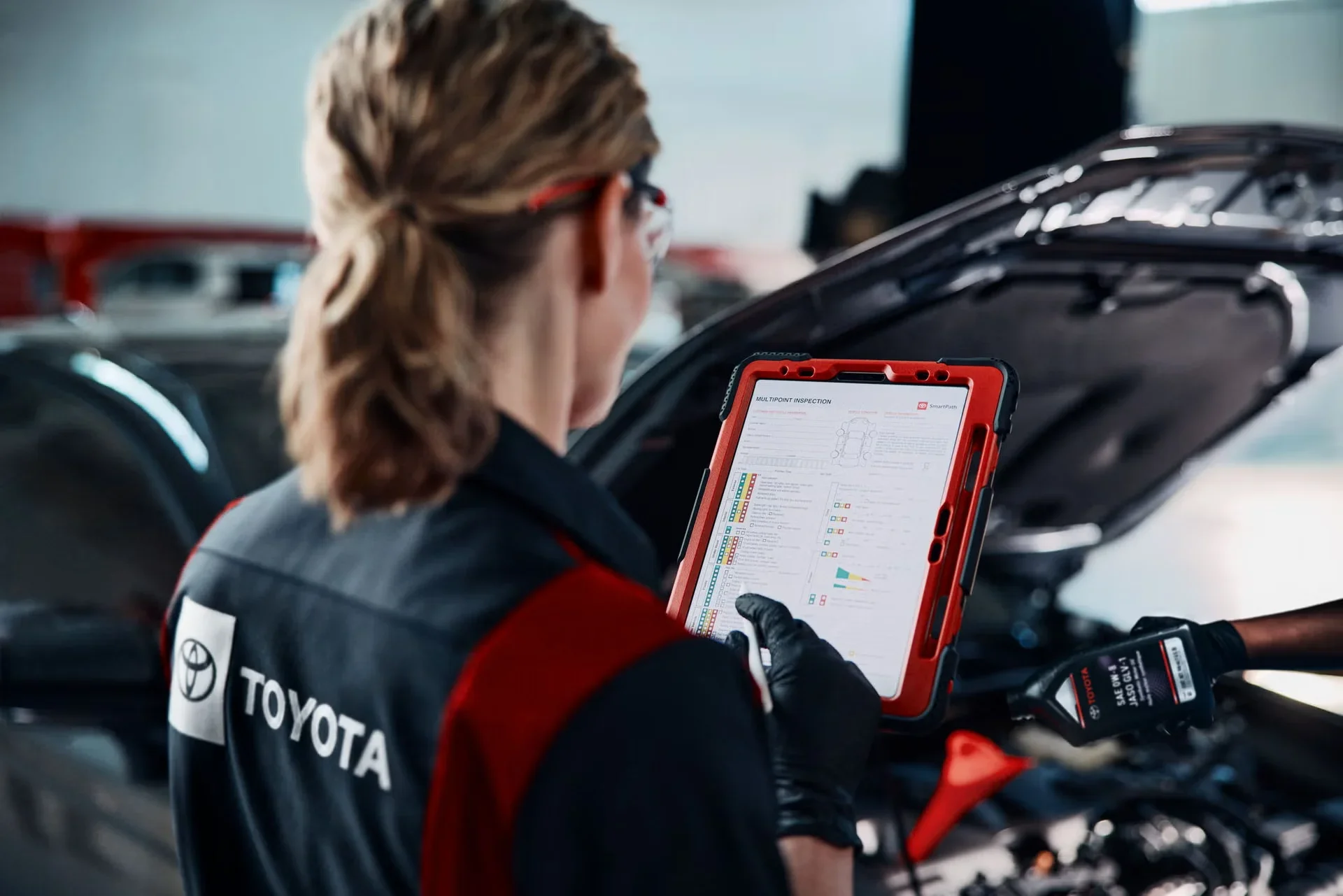 Two Toyota technicians doing an oil change and a multipoint inspection in the service garage