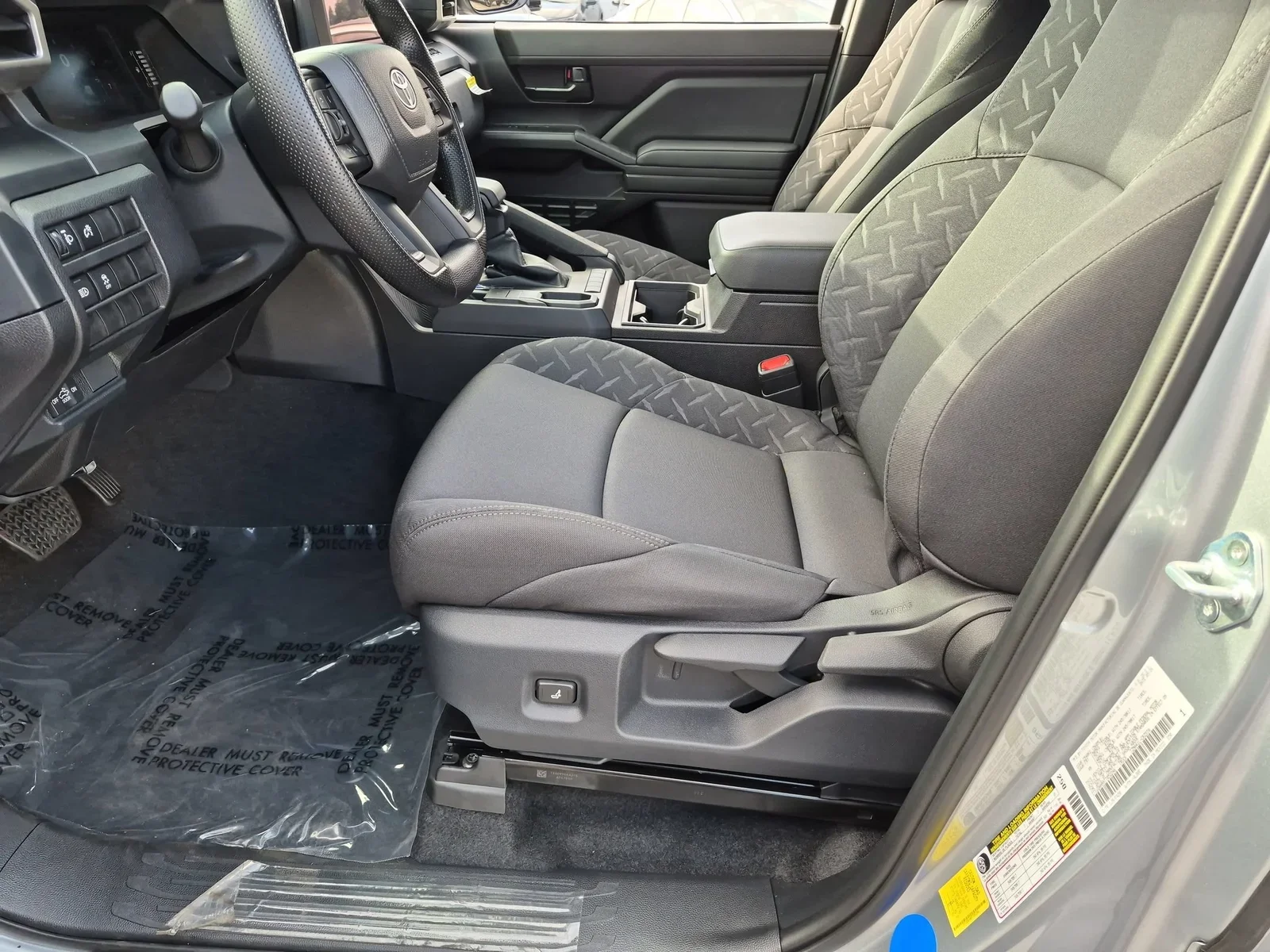 The front cloth seats of a 2026 Toyota Tacoma with the driver's door open