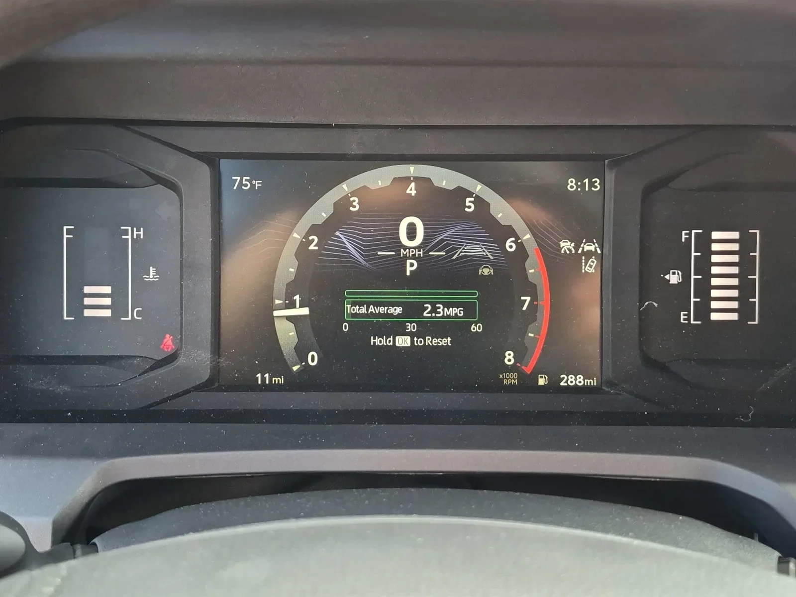 The digital instrument cluster of a new Toyota Tacoma showing 11 miles on the odometer