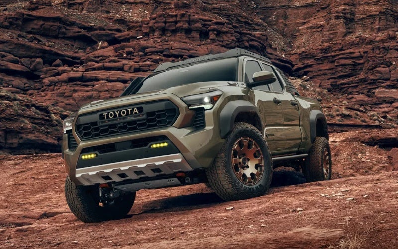A Toyota Tacoma TRD on a rocky off-road trail, showing its ground clearance and all-terrain stance.