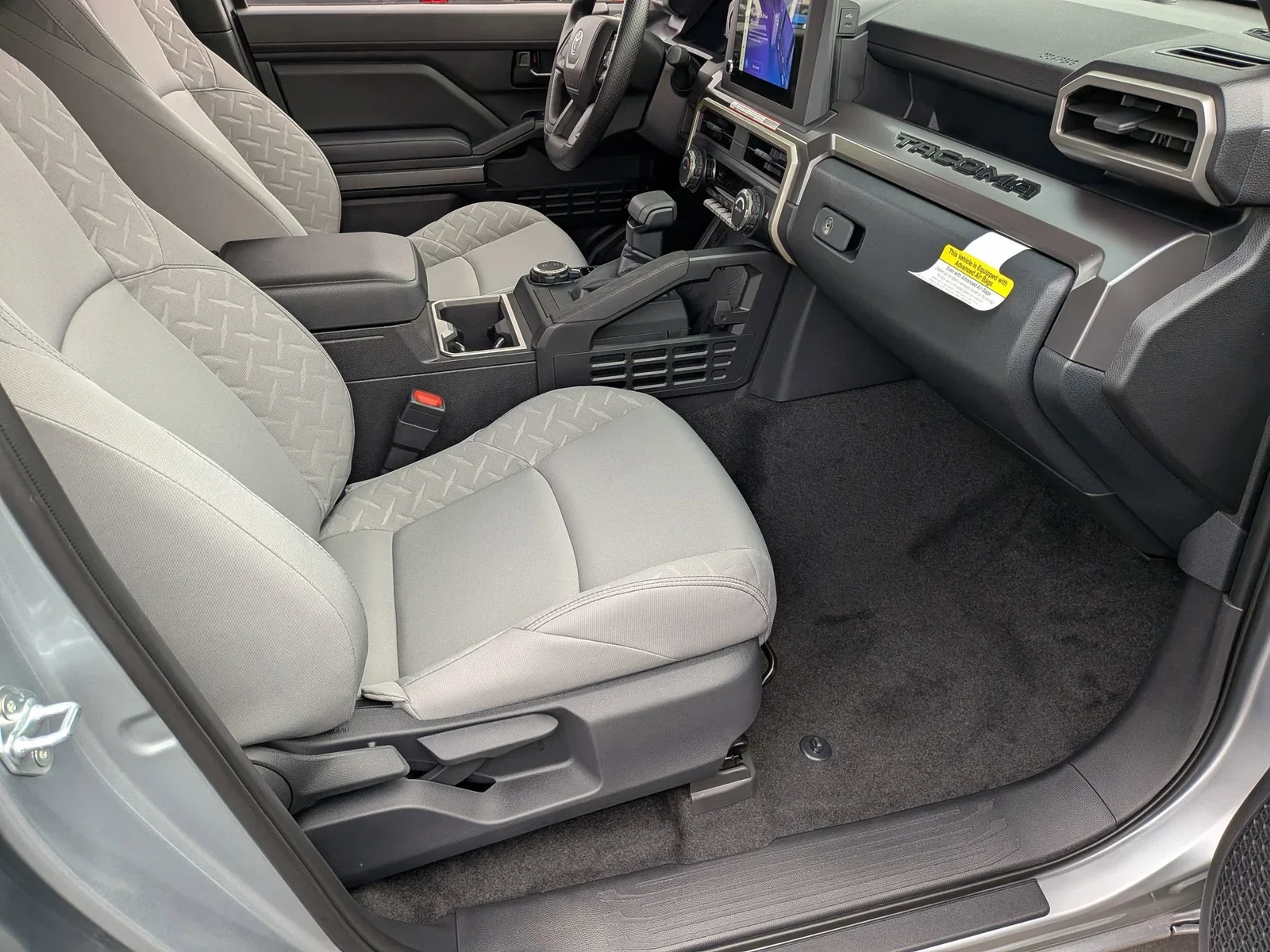Front cloth seats and TACOMA-badged dashboard inside a Toyota Tacoma